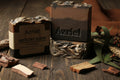 Two bars of Azriel soap on a wooden surface with natural elements.