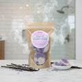 Lavender Vanilla Shower Steamer in a clear packaging with a purple label on a cardboard background.