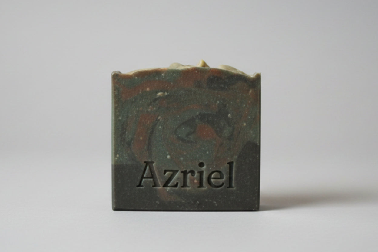 Bronze square object with 'Azriel' engraving on a cardboard background