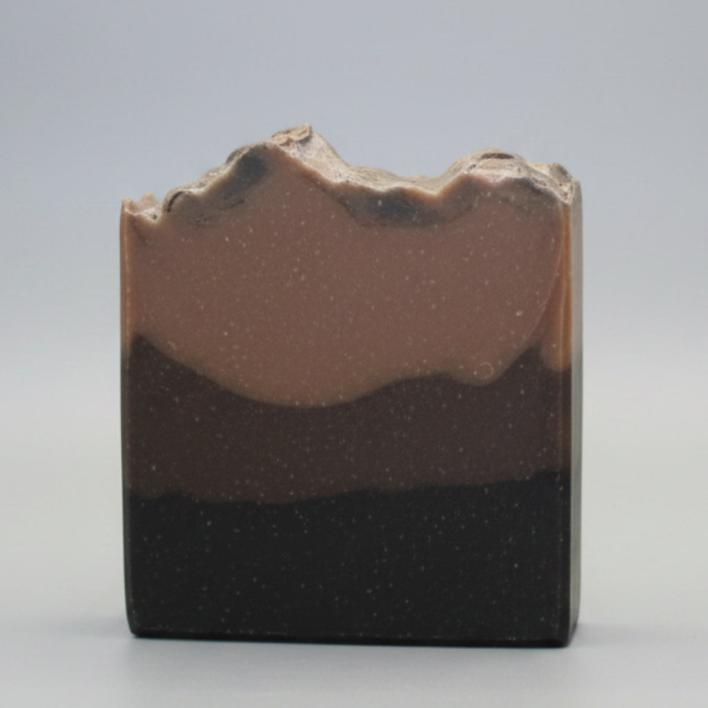 Three-layered soap bar on a beige surface with a neutral background
