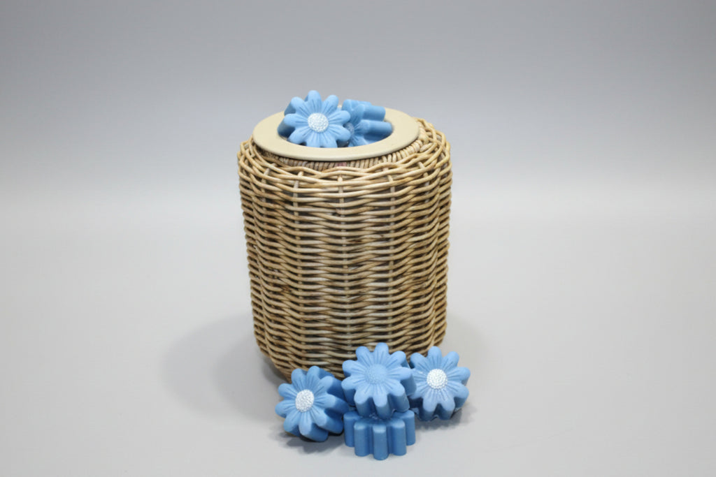 Wicker basket with blue flower-shaped objects on a tiled bathroom floor.