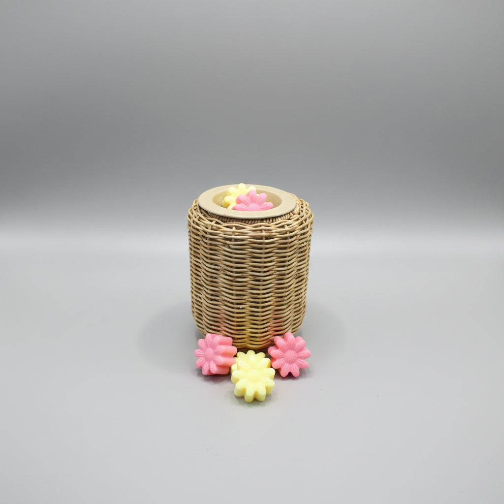 Wicker basket with lit candles and flower-shaped candles on a cardboard surface