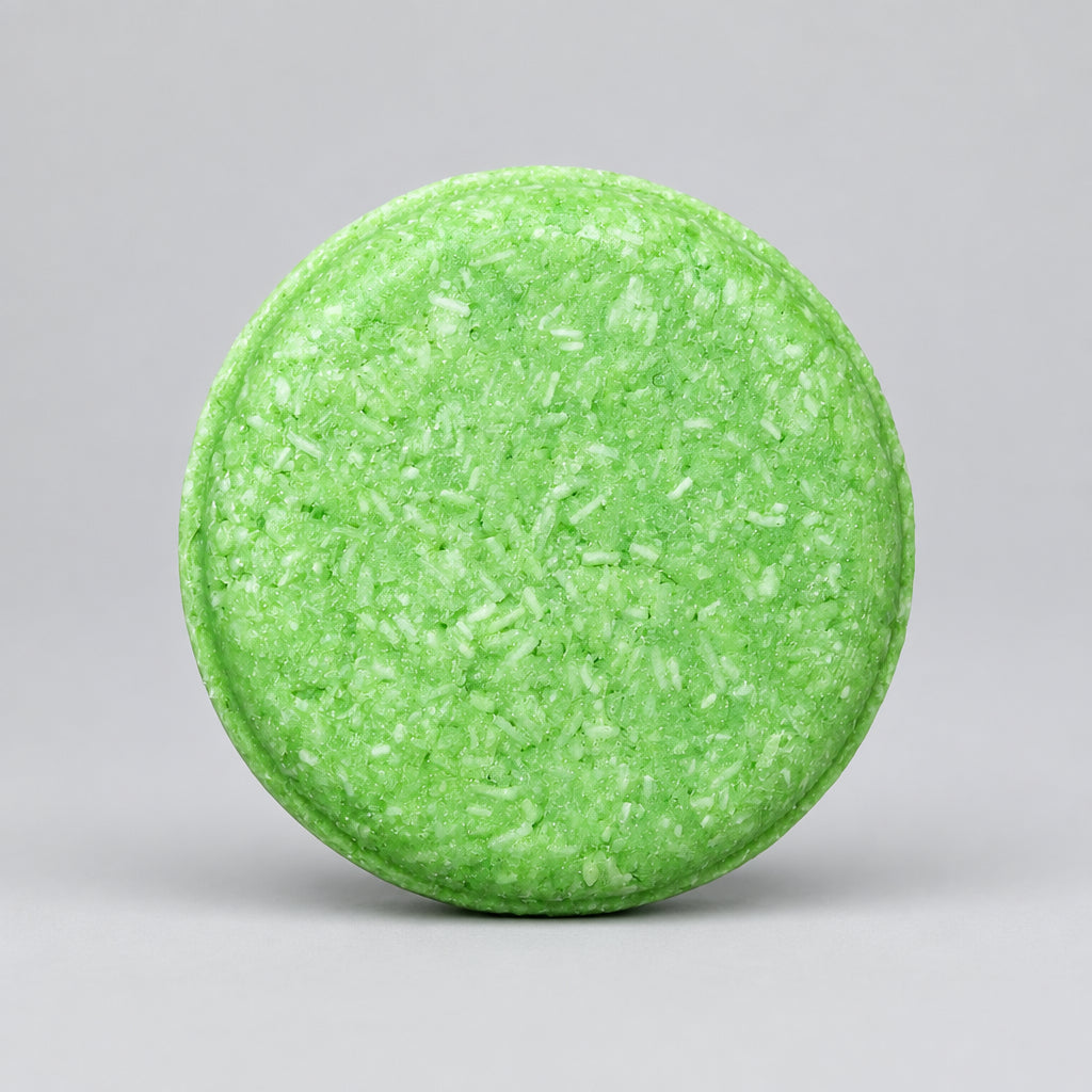 A round, light green soap bar with a textured, crumbly surface, photographed from directly above on a neutral beige background.