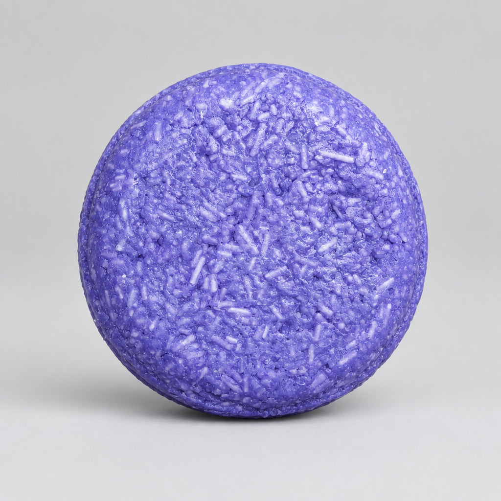 A round purple macaron with a textured, crumb-coated top, presented on a wooden surface.