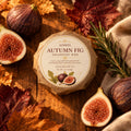 A round handmade shampoo bar wrapped in brown kraft paper with a white circular label reading 'AZRIEL AUTUMNFIG SHAMPOO BAR' and showing fig illustrations, placed on a wooden surface.